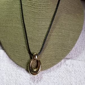 Goldtone shiny pendant on black cord necklace